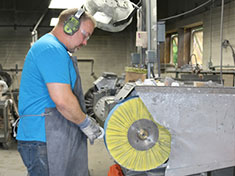 Guy wearing ear protection gear at Buffing Wheel using Yellow Buffer to Polish a Part